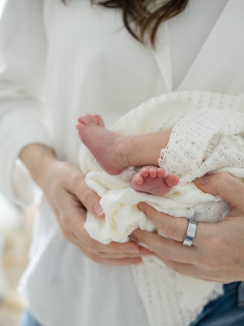 Newborn feet held gently in a mother's hands